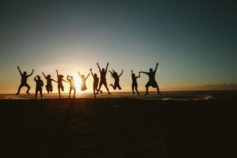 Multiple happy people jumping, watching a sunrise.