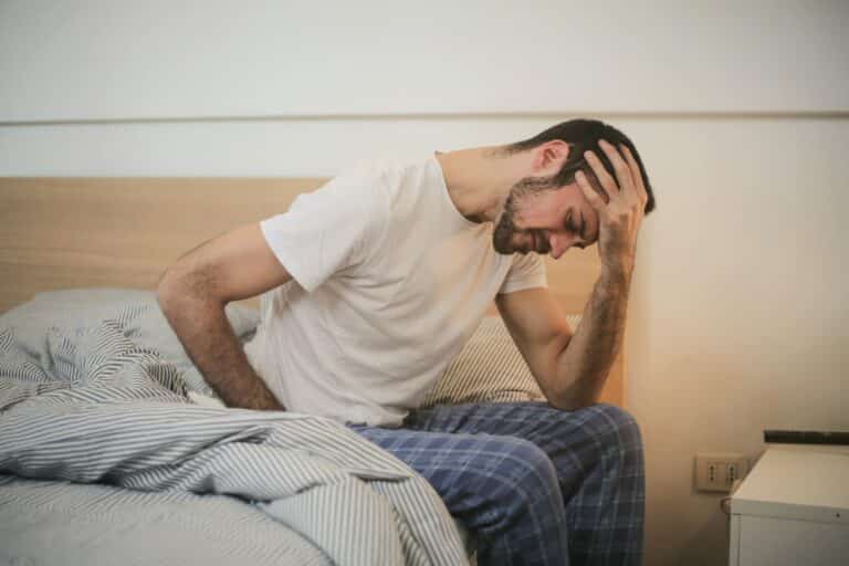 man sitting on his bead, his head resting on his hand, he looks like he's hurting