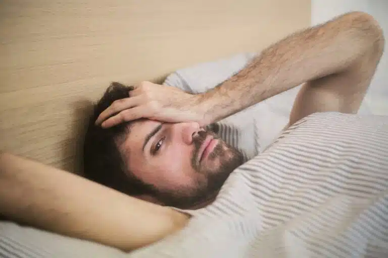 Ein Malnn liegt mit Kopfschmerzen im Bett: Hilfe bei Kater (Hangover Relief)